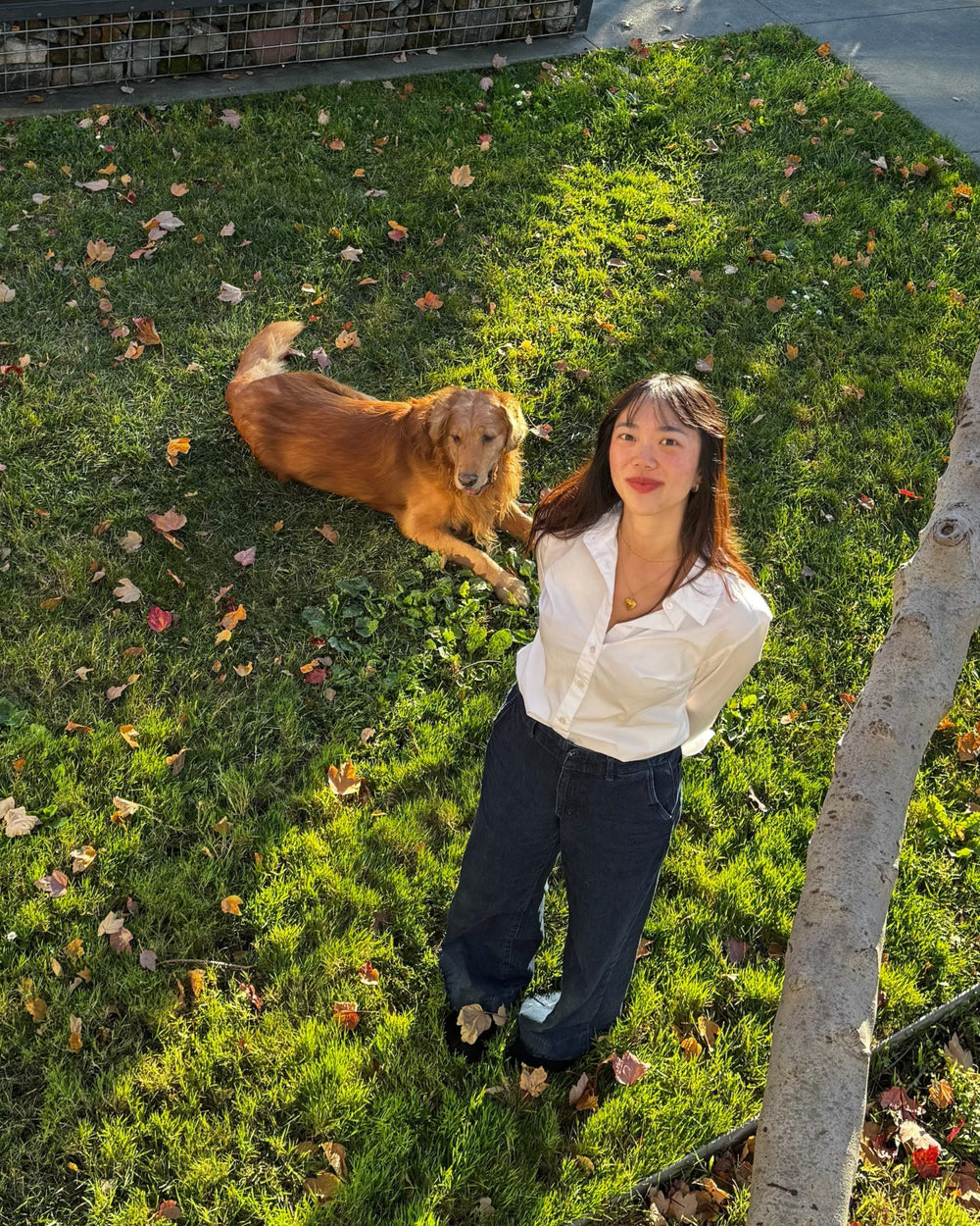 Woman standing on grass with a dog in a park setting